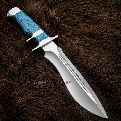 A fixed-blade knife with a polished silver steel blade and a textured turquoise blue handle with black veining, resting on a dark brown fur background. The brand name 'ARHAM CUTLERY' is watermarked across the center.