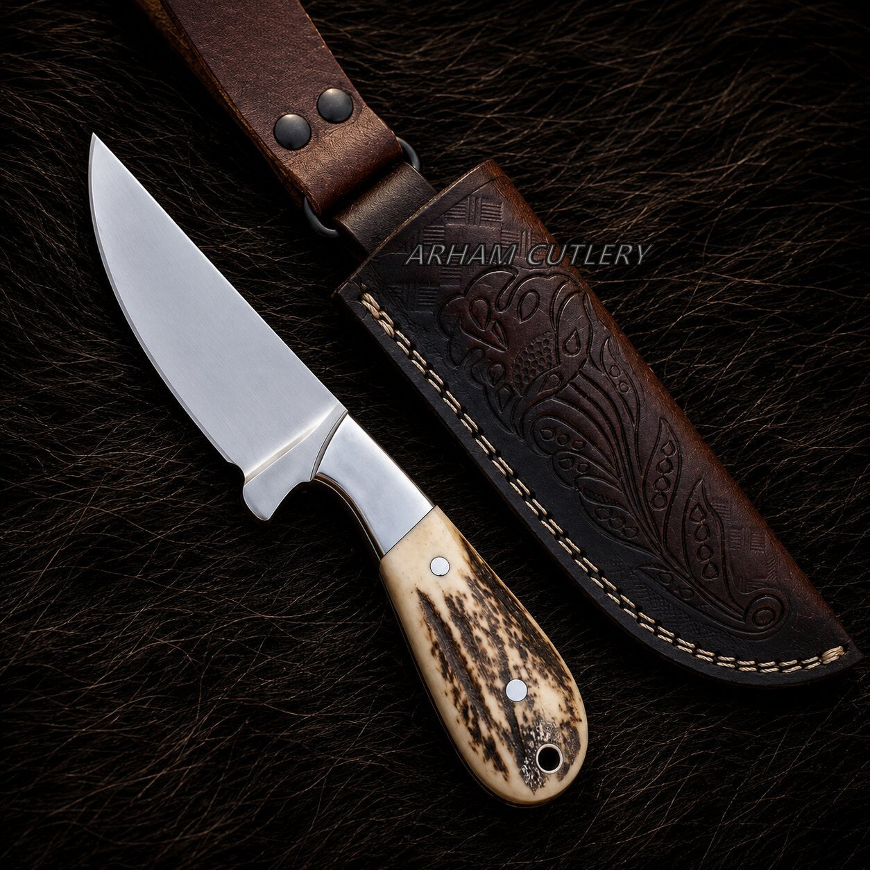 A fixed-blade knife with a polished silver blade, a silver bolster, and a carved bone handle with dark brown veining, displayed next to its dark brown embossed leather sheath on a dark textured background. A watermark for 'ARHANT CUTLERY' is visible.