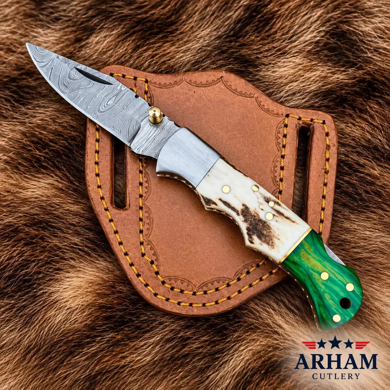 A folding pocket knife with a Damascus steel blade, a bone handle, and a green mother-of-pearl handle end, resting on a brown leather sheath over a brown fur background. The 'ARHAM CUTLERY' logo is visible in the bottom right corner.