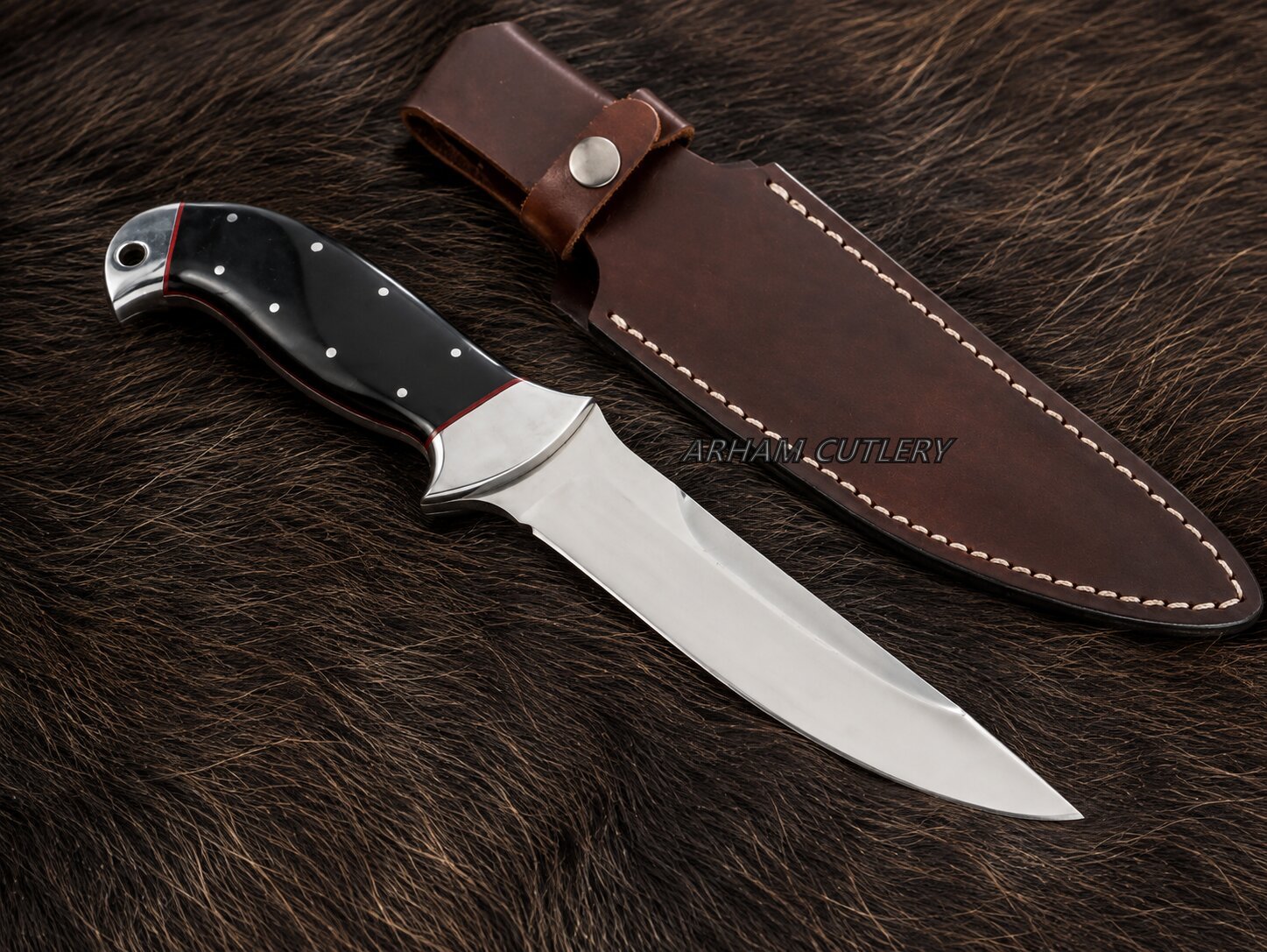 A fixed-blade knife with a silver blade and black handle with silver rivets, displayed next to its brown leather sheath on a dark brown fur background. A faint watermark 'ARSHAD CUTLERY' is visible across the center.