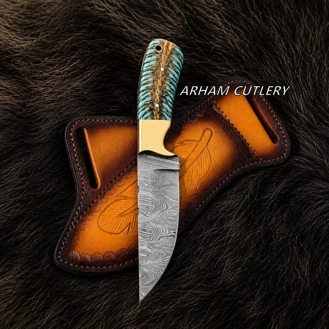 A fixed-blade knife with a patterned steel blade, turquoise and brown wrapped handle, and brass bolster, displayed upright in front of a brown leather sheath on a dark fur background. The text 'ARHAM CUTLERY' appears on the right.