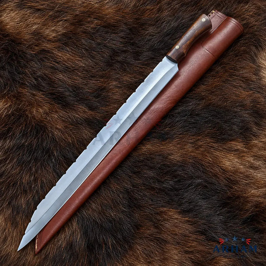 A long fixed-blade knife with a silver steel blade and dark brown wooden handle, shown alongside a brown leather sheath on a brown animal fur background. A small 'Artem' logo is visible in the bottom right corner.